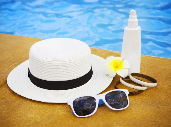 Crema solare, occhiali da sole, cappello, bracciale vicino alla piscina — Foto Stock