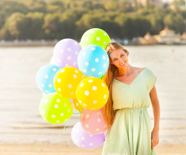 Woman on the beach with colored polka dots balloons — Stock Photo, Image