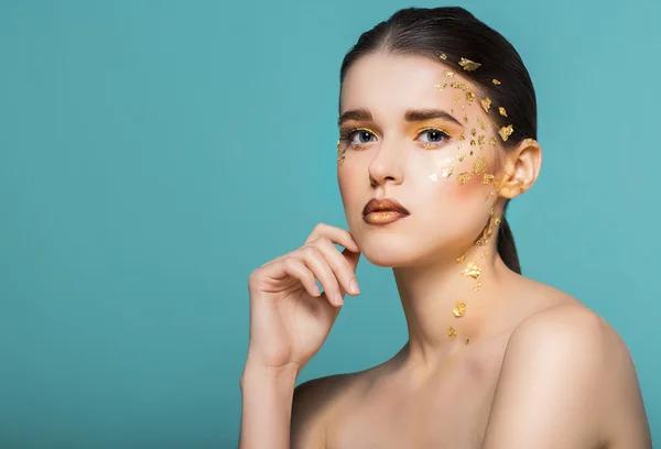 Retrato de uma bela jovem com maquiagem dourada brilhante — Fotografia de Stock