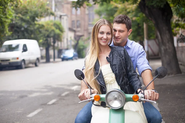 Happy young couple by a vintage scooter on the street — Stock Photo, Image