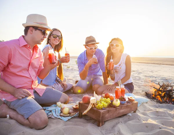 Amis assis sur le sable à la plage et boire de la limonade — Photo