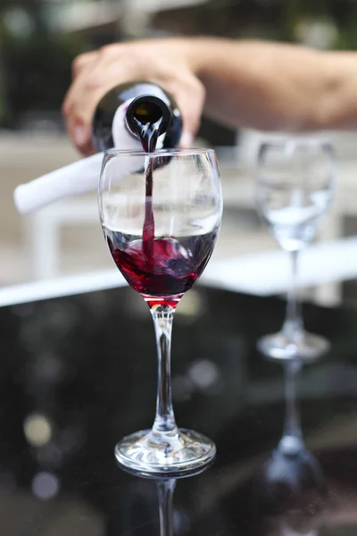 Despejando vinho tinto da garrafa para o copo de vinho — Fotografia de Stock