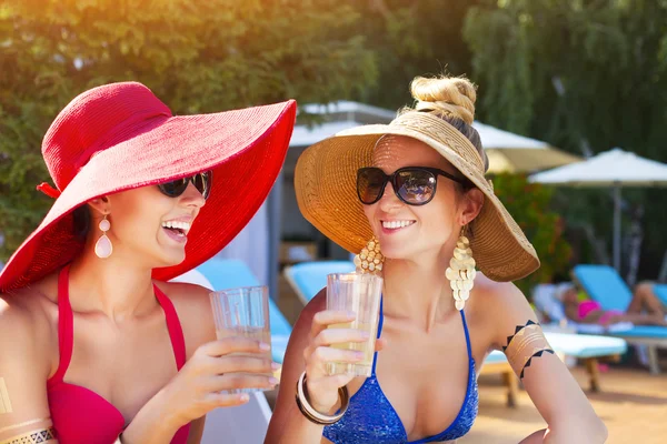 Vrouwen drinken een cocktail terwijl u ontspant bij het zwembad — Stockfoto