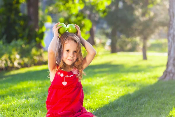 Niña divertida con manzanas verdes en el parque de verano —  Fotos de Stock