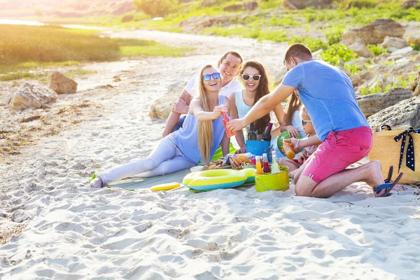 Vänner sitter på sanden på stranden på sommaren picknick — Stockfoto