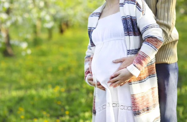 Happy pregnant couple in the blossom garden — Stock Photo, Image