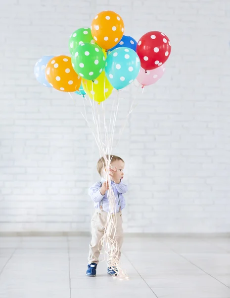 Liten pojke håller en massa färgade ballonger — Stockfoto