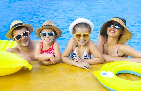 Счастливая семья с двумя детьми развлекается в бассейне — стоковое фото
