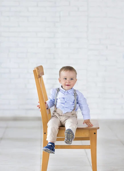 Schöne entzückende lachende Baby-Junge sitzt auf dem Stuhl. — Stockfoto