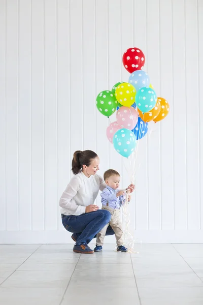 Liten pojke med hans mamma hålla en massa färgade ballonger — Stockfoto