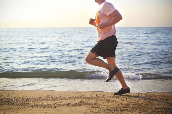 Чоловік біжить на пляжі на заході сонця — стокове фото
