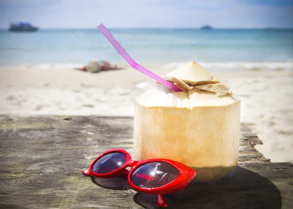 Cóctel de coco fresco y gafas de sol rojas en la playa — Foto de Stock