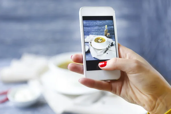 Woman taking a photo of fish soup with smartphone — Stock Photo, Image