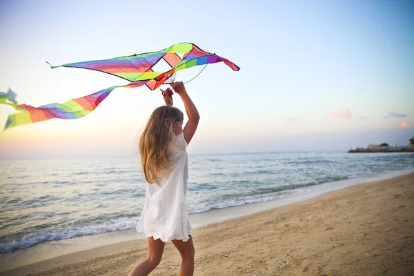 Κοριτσάκι με πετούν χαρταετό σε τροπική παραλία στο ηλιοβασίλεμα — Φωτογραφία Αρχείου