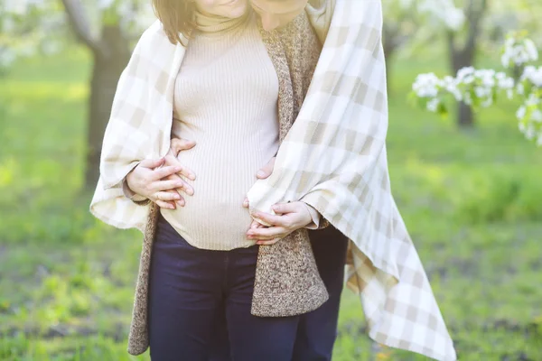 Feliz pareja embarazada en el jardín de flores —  Fotos de Stock