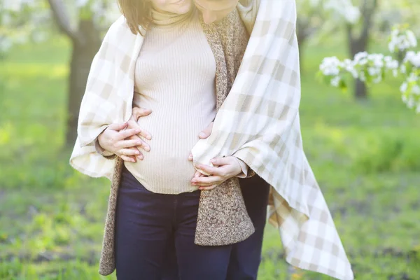 Happy pregnant couple in the blossom garden — Stock Photo, Image