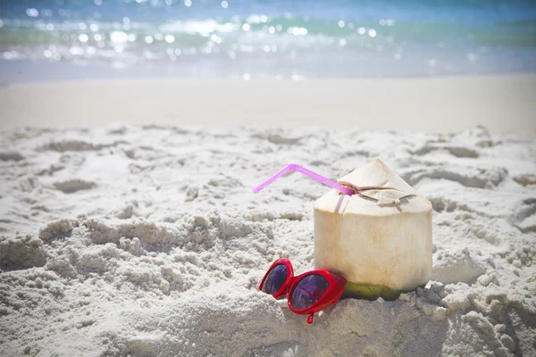 Taze hindistan cevizi kokteyl ve kırmızı güneş gözlüğü sahilde — Stok fotoğraf