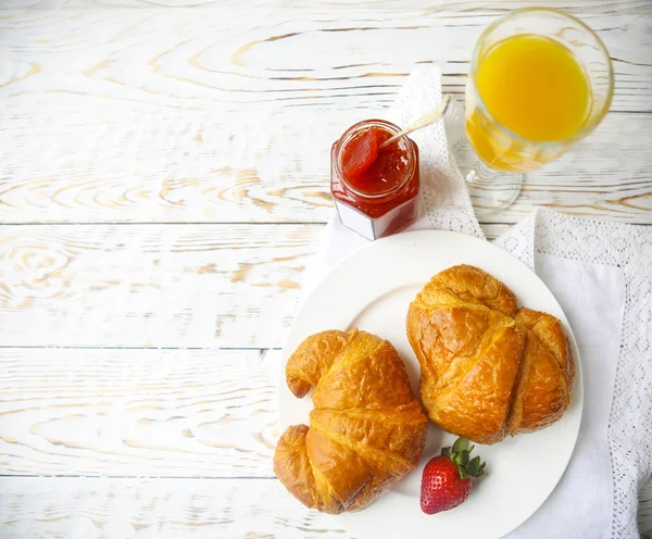 Dos croissants sabrosos en el plato y mermelada de fresa — Foto de Stock