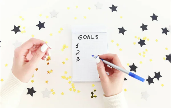 Weibliche Hand Mit Stift Schreibt Neujahrsziele Leeres Notizbuch Auf Weißem — Stockfoto