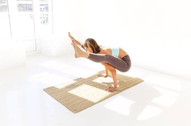 Spor kıyafetli sakin bir kadının Firefly pozunda yoga yaparken kollarını mindere koyup bakışlarını kaçırması.