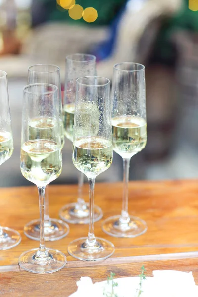 Uppsättning Champagneglas Träbord Med Ljus Mot Suddig Vägg Med Julgran — Stockfoto