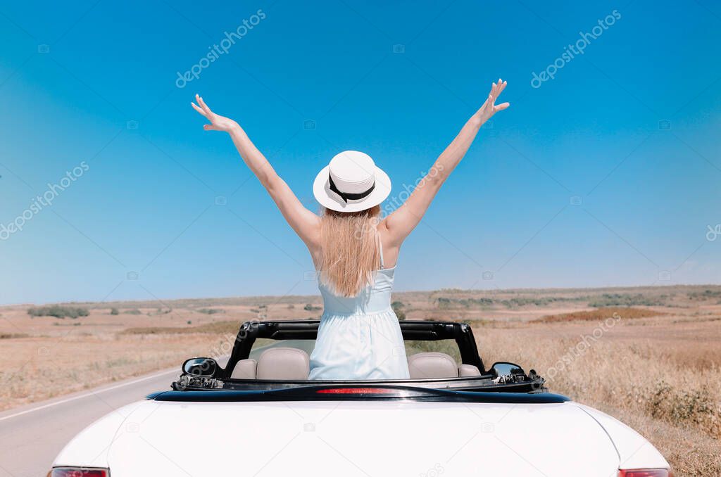Back view of joyful young female in summer clothes in cabriolet during road trip