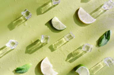 Yeşil zemin üzerinde limon ve damlacıklı taze nane yaprağı ve buz küpleri. Yaz arkaplanı