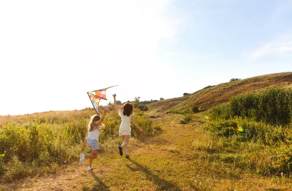 ケアフリー女性と十代の女の子がフィールドに沿って実行し 夏の週末にカイトと遊ぶ — ストック写真