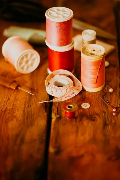 テーラーワークショップでは 木材テーブルの糸の近くに配置されたテープ測定と針 — ストック写真