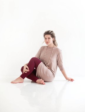 Renkli kıyafetli neşeli bir bayan kameraya bakıp gülümsüyor ve beyaz arka planda izole edilmiş rastaları sallıyor.