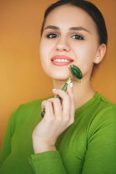 Smiling Charming Female Massaging Face Jade Roller Skincare Procedure Beige — Stock Photo, Image