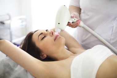 Yüzünün lazer epilasyonu sırasında güzellik salonundaki kanepede uzanan kadın müşteriden.