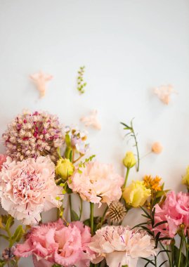 Açık mavi arkaplanda güzel kompozisyonlarda sıralanmış organik taze çiçeklerin üst görüntüsü