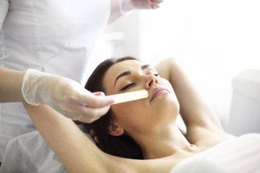 Tanınmayan kozmetik uzmanı güzellik salonundaki genç bir kadının yüzüne jel sürüyor.