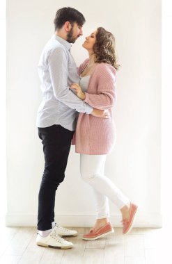 Memlekette beyaz arka planda kucaklaşan içerik seven çiftin yan görünümü