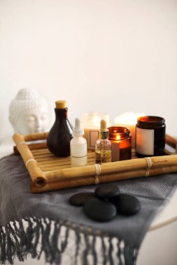 Evdeki masaya çeşitli cilt bakım ürünleri konmuş mumlar ve kaplar yakıyor.