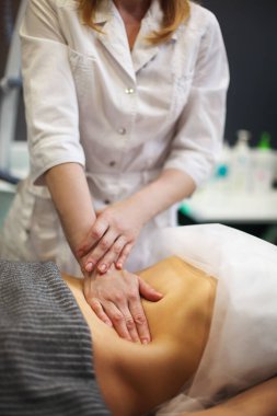 Masörün, masaj masasında kadınlara karın masajı yaptığı kısmen görülüyor.