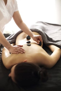 Spa merkezinde sıcak taş terapisi sırasında masada uzanan tanınmayan bir kadın.