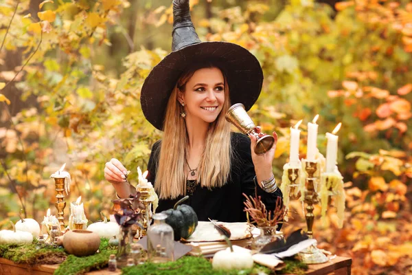 Молодая Женщина Костюме Ведьмы Сидит Столом Волшебными Ингредиентами Делает Заметки — стоковое фото