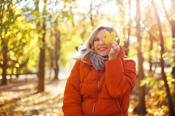 秋の公園の日当たりの良い週末には アウターウェアの女性が笑顔で目を覆います — ストック写真