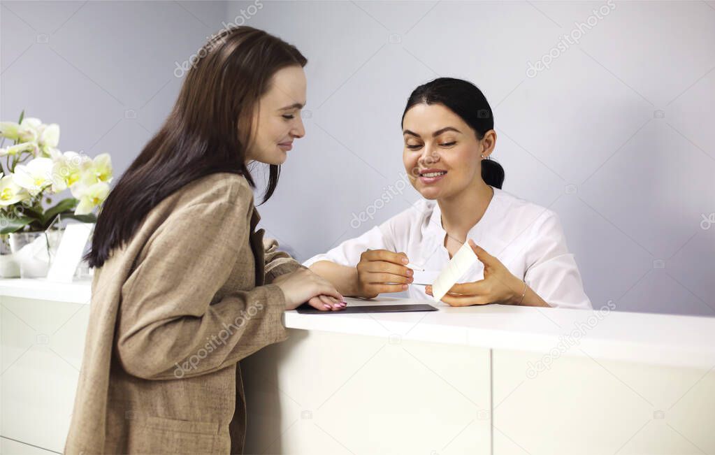 Young female receptionist working in beauty salon and talking with female customer