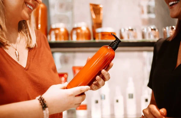 Profesjonalny Kosmetyk Omawiający Produkt Leczniczy Klientką Stojąc Przy Półkach Kosmetykami — Zdjęcie stockowe