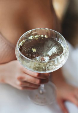 Yukarıdan, elinde cam bardak köpürten şampanya kadehiyle, isimsiz bir kadının şölenin tadını çıkarması geliyor.