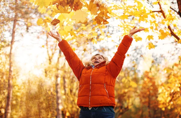 秋の公園で日当たりの良い週末に乾燥した葉で笑顔で外服で楽しい女性 — ストック写真