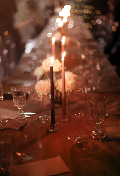 夜は皿やグラスゴブレットの近くの宴会テーブルに置かれたろうそくや新鮮な花を燃やす — ストック写真