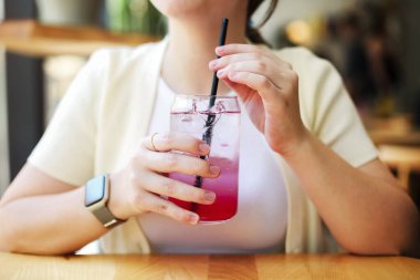 Tanımlanamayan bir kadın, yaz aylarında restoranda oturmuş ve taze soğuk bir içecek içiyor.