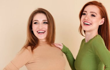 Mutlu kızıl kadın kız arkadaşının omzuna dokunuyor ve gülümsüyor.