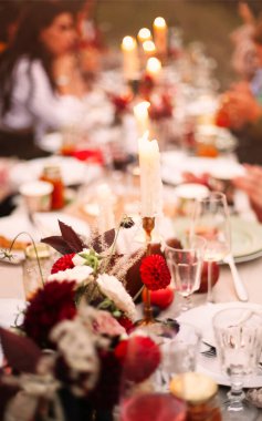 Etkinlik sırasında sofra masasının üzerine yerleştirilmiş taze çiçeklerin ve yanan mumların yumuşak odağı