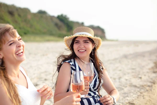 海の近くの砂浜でワインを楽しみながら笑顔で夏の衣装で幸せな大人の女性の友人 — ストック写真