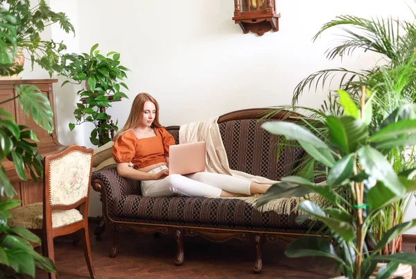 Barefoot Female Using Netbook While Relaxing Elegant Couch Amidst Lush — ストック写真